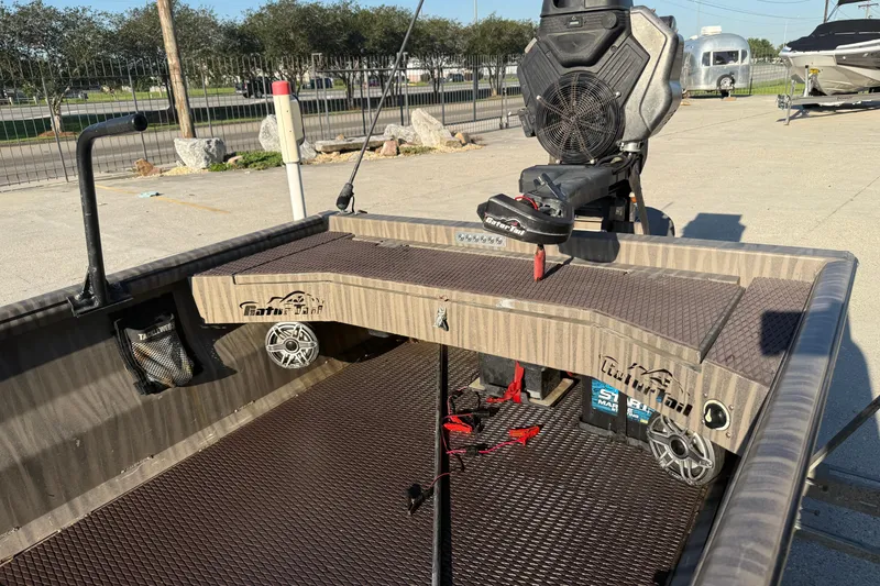 Slide: The Image of 2023 Gator Tail 1852 boat interior with seating and equipment, parked outdoors. - 7
