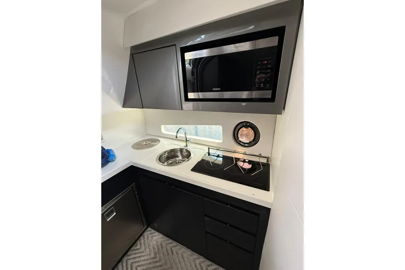 Slide: The Image of Compact kitchen in 2023 Schaefer 400 Sport yacht with microwave, sink, and stove. - 11