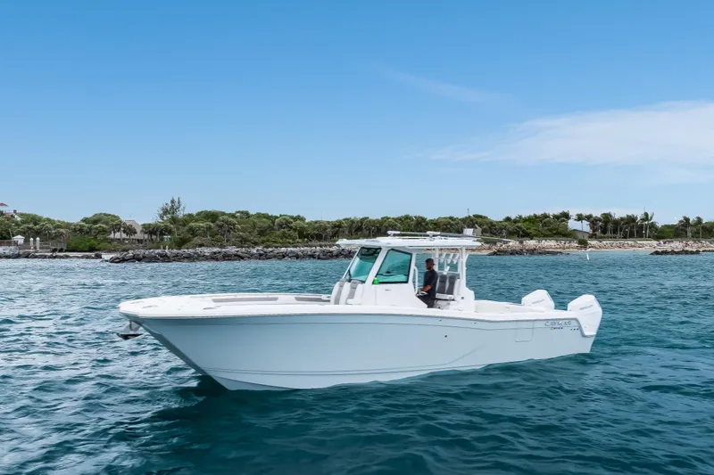 The Image of 2024 Caymas 341 CC boat cruising on a clear blue ocean near a rocky shoreline. - 1