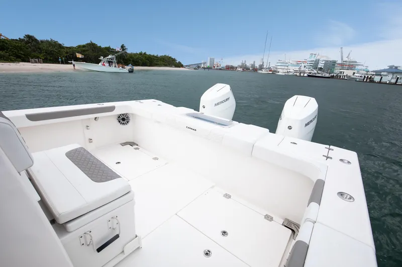 Slide: The Image of 2024 Caymas 341 CC boat with dual Mercury engines on calm water near a marina. - 10