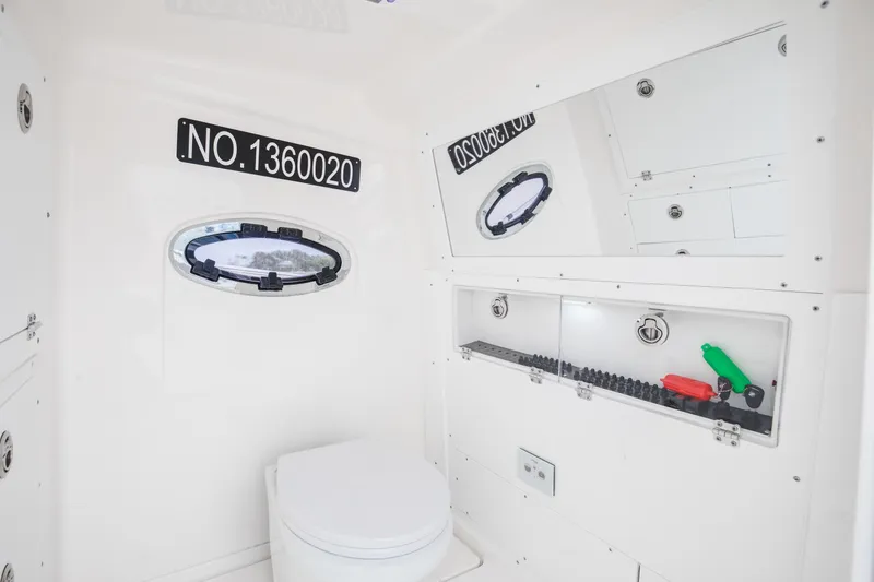 Slide: The Image of 2024 Caymas 341 CC boat interior with toilet, storage, and porthole window. - 11