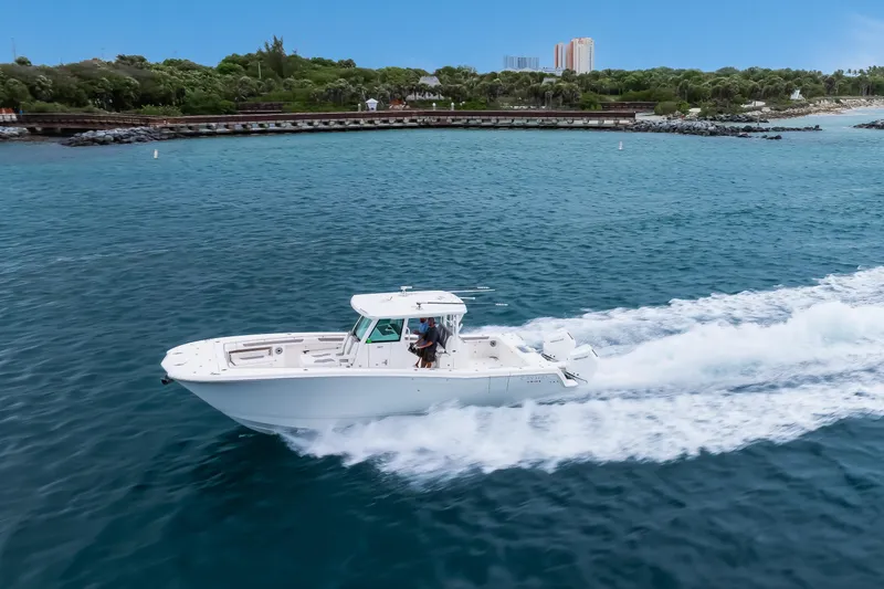 Slide: The Image of 2024 Caymas 341 CC boat cruising on blue ocean near lush coastline. - 13