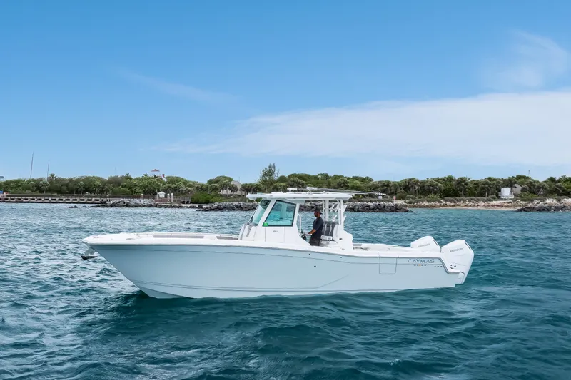 Slide: The Image of 2024 Caymas 341 CC boat cruising on blue ocean near lush coastline. - 14
