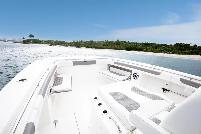 Slide: The Image of 2024 Caymas 341 CC boat interior with white seating, near a scenic shoreline. - 9