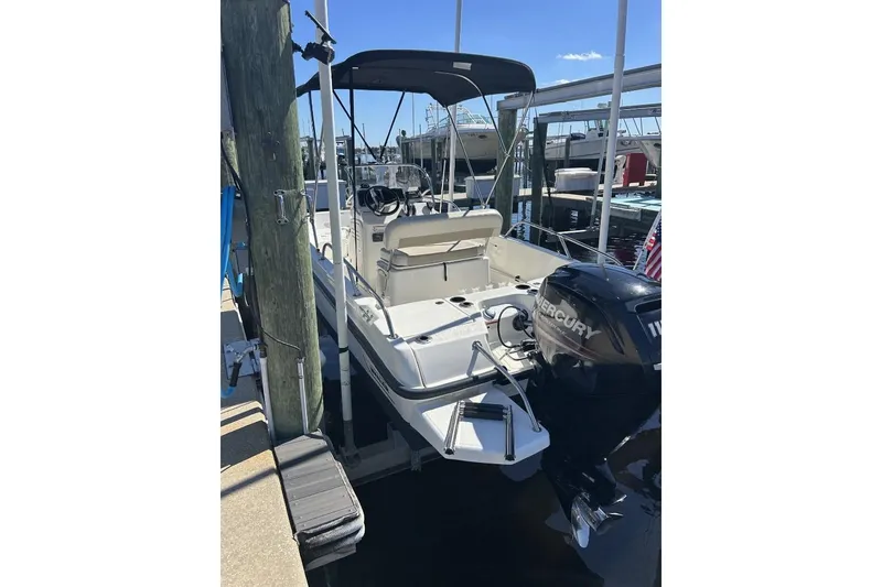 Slide: The Image of 2019 Boston Whaler 170 Dauntless boat docked with Mercury engine, featuring a canopy. - 3