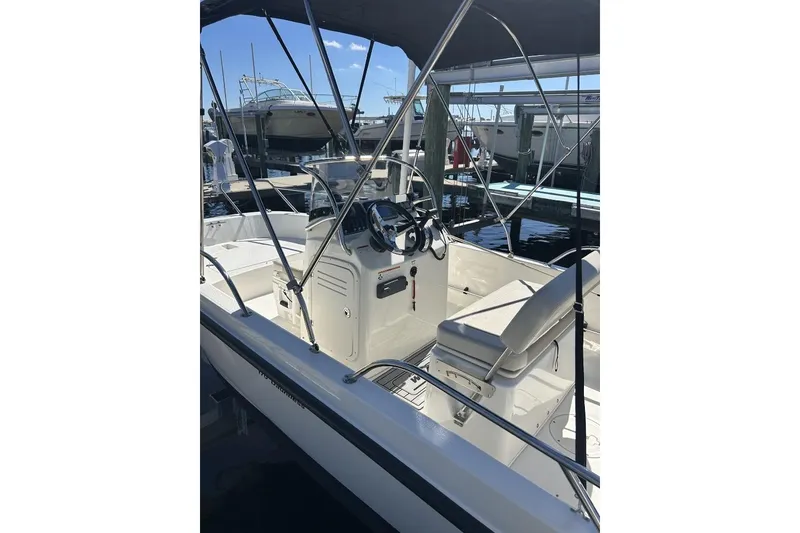 Slide: The Image of 2019 Boston Whaler 170 Dauntless boat interior with steering console and seating at marina. - 5