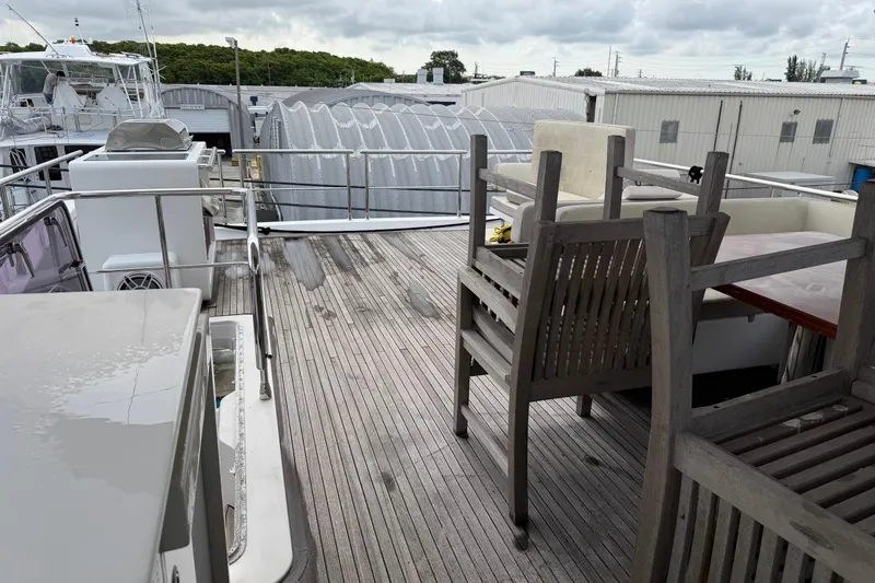 Slide: The Image of Azimut Fly 72 yacht deck with stacked chairs, 2017 model, in a marina setting. - 11