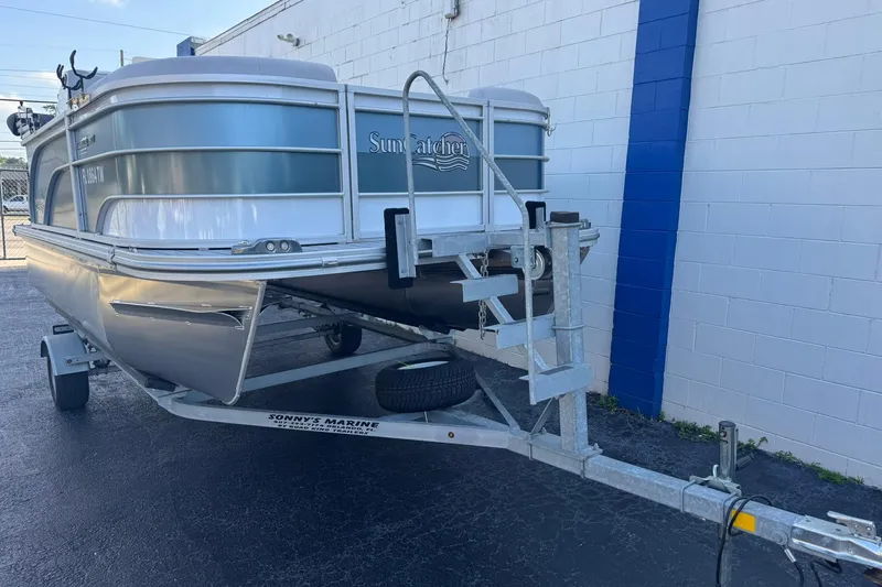 Slide: The Image of 2024 SunCatcher Select 16C pontoon boat on trailer, parked by a white wall. - 5