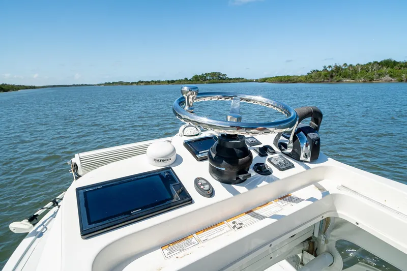 Slide: The Image of 2018 SeaVee 270Z boat helm with Garmin navigation, steering wheel, and throttle controls on open water. - 49