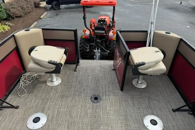 Slide: The Image of 2022 Viaggio Lago 18F pontoon boat interior with two swivel seats and a tractor in the background. - 9