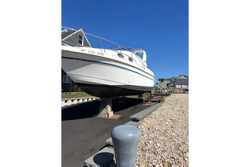 Slide: The Image of 1997 Donzi 255 LXC boat on blocks, parked near a pebble driveway. - 2