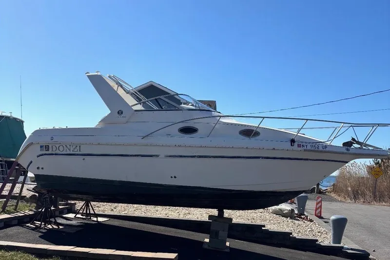 The Image of 1997 Donzi 255 LXC boat on dry dock, sunny day, grassy foreground. - 0