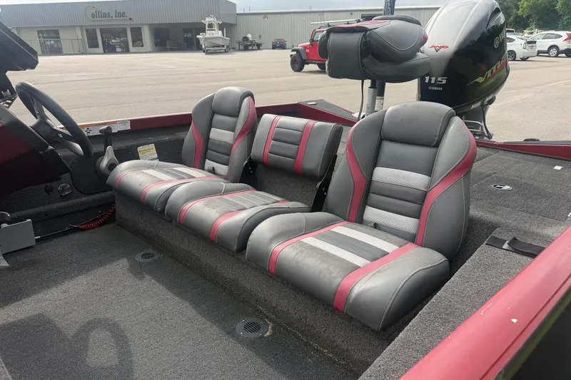 Slide: The Image of 2019 Ranger RT188 boat interior with gray and red seating, parked near a building. - 7