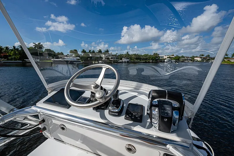 Slide: The Image of Cockpit view of 2022 Bahama 41 boat with steering wheel and controls on a sunny day. - 16