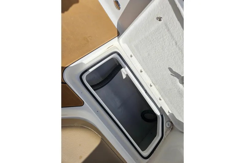 Slide: The Image of Open storage compartment on 2026 Bayliner V20 boat, featuring white interior and secure latch. - 10