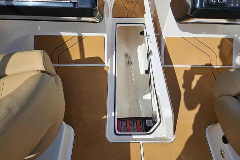 Slide: The Image of 2026 Bayliner V20 boat interior with tan seats and open storage compartment. - 13