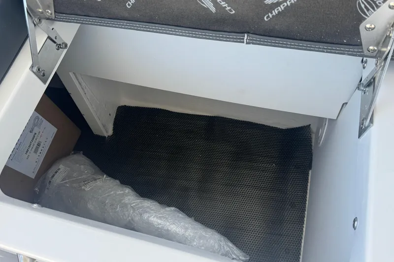 Slide: The Image of Storage compartment in 2026 Chaparral SSX 30 boat, featuring black mat and packaging materials. - 32