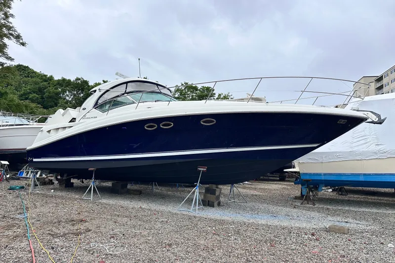 Slide: The Image of 2005 Sea Ray 390 Sundancer yacht on dry dock, blue hull, white deck, overcast sky. - 1