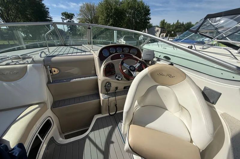 Slide: The Image of 2009 Sea Ray Sundancer 280 cockpit with steering wheel and dashboard, under clear blue sky. - 3