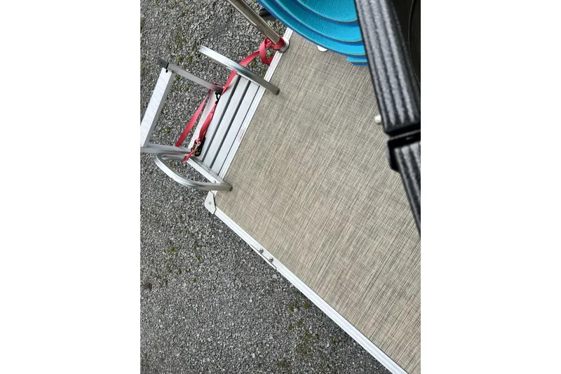 Slide: The Image of 2016 Crest I 220 boat deck with ladder and blue seats on gravel surface. - 9