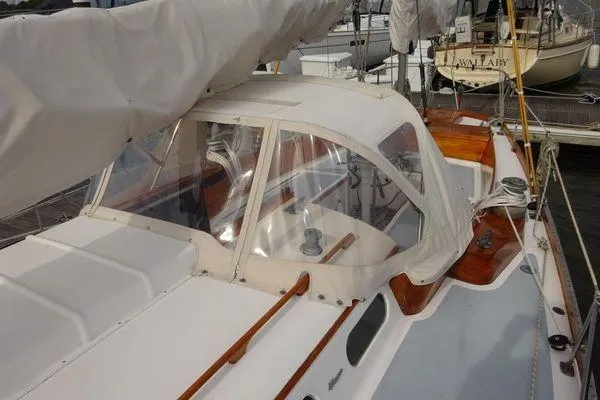 Slide: The Image of 1964 Hinkley Bermuda 40 sailboat with covered cockpit and wooden accents at a marina. - 11