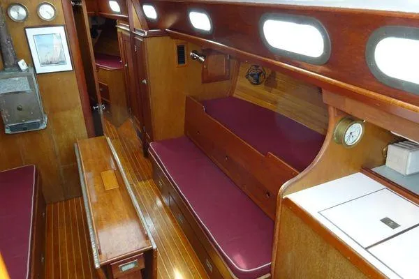 Slide: The Image of Interior of a 1964 Hinkley Bermuda 40 sailboat with wooden furnishings and maroon cushions. - 16