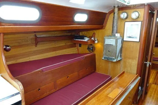 Slide: The Image of Interior of a 1964 Hinkley Bermuda 40 sailboat with wooden furnishings and maroon cushions. - 17