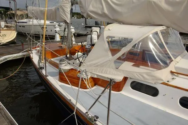 Slide: The Image of 1964 Hinkley Bermuda 40 sailboat docked, featuring classic wooden deck and white sails. - 2