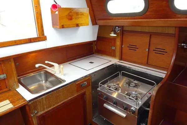 Slide: The Image of 1964 Hinkley Bermuda 40 yacht kitchen with stove, sink, and wooden cabinetry. - 23