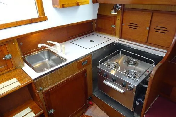 Slide: The Image of 1964 Hinkley Bermuda 40 yacht kitchen with stove, sink, and wooden cabinetry. - 25