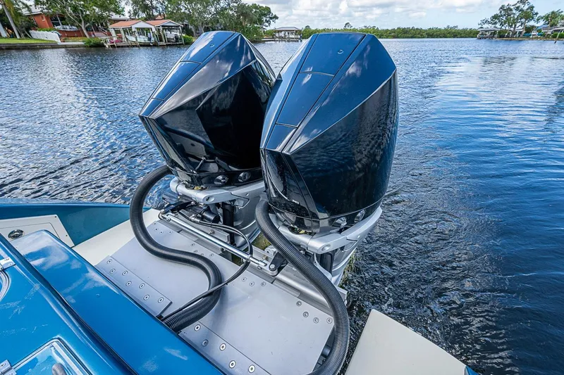 Slide: The Image of Twin outboard motors on a 2002 True North 38 boat, docked on a serene lake. - 17