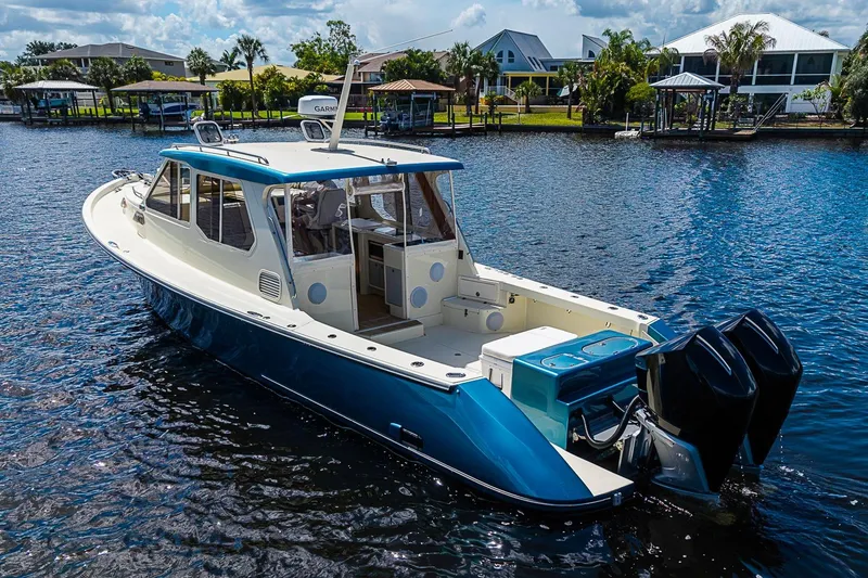 Slide: The Image of True North 38 boat from 2002 on a scenic waterfront, featuring dual outboard motors. - 7