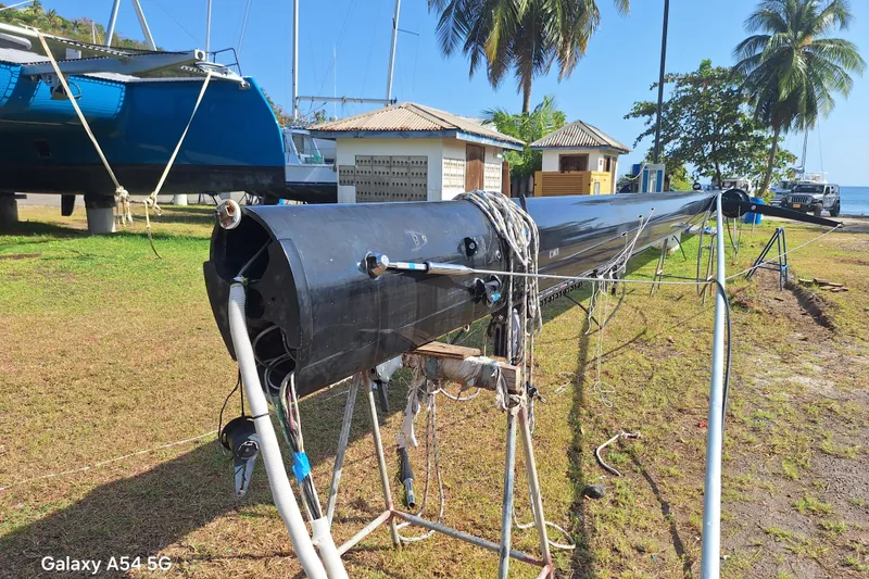 Slide: The Image of Sailboat mast from a 2011 Alibi 54, resting on stands near the ocean. - 16