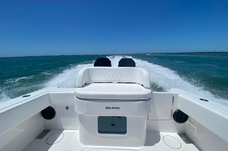 Slide: The Image of 2027 Reef Runner 340 boat cruising on open water under clear blue sky. - 21