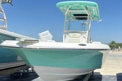The Image of 2021 Caymas 26 HB boat with turquoise hull and T-top, docked outdoors. - 1