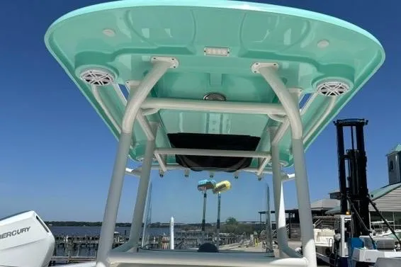 Slide: The Image of 2021 Caymas 26 HB boat with teal T-top and speakers, docked at marina. - 12