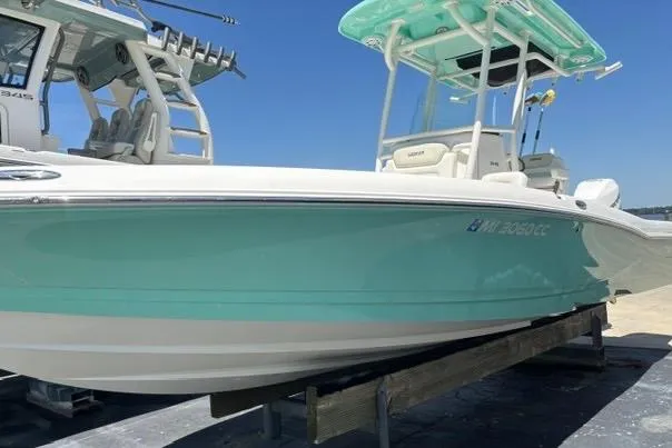 Slide: The Image of 2021 Caymas 26 HB boat with turquoise hull on display at a marina. - 2