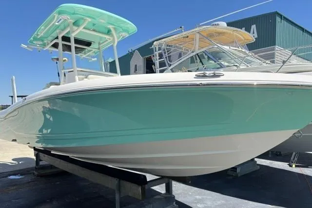 Slide: The Image of 2021 Caymas 26 HB boat with teal hull and T-top, docked outdoors. - 3