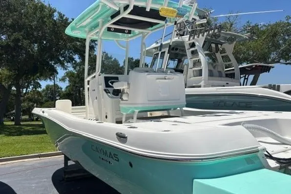 Slide: The Image of 2021 Caymas 26 HB boat with teal accents, docked outdoors on a sunny day. - 5
