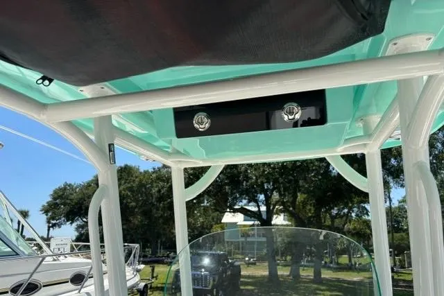 Slide: The Image of 2021 Caymas 26 HB boat with teal canopy and white frame, parked outdoors. - 7