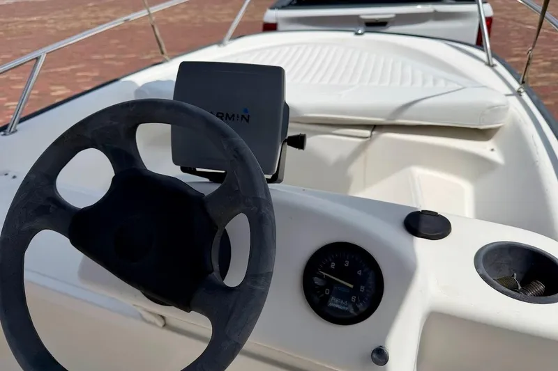 Slide: The Image of 2002 Boston Whaler 130 Sport boat interior with steering wheel and navigation system. - 11