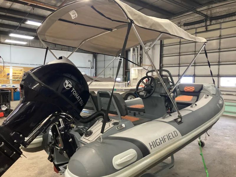 Slide: The Image of 2023 Highfield Sport 360 inflatable boat with Tohatsu engine in workshop. - 2