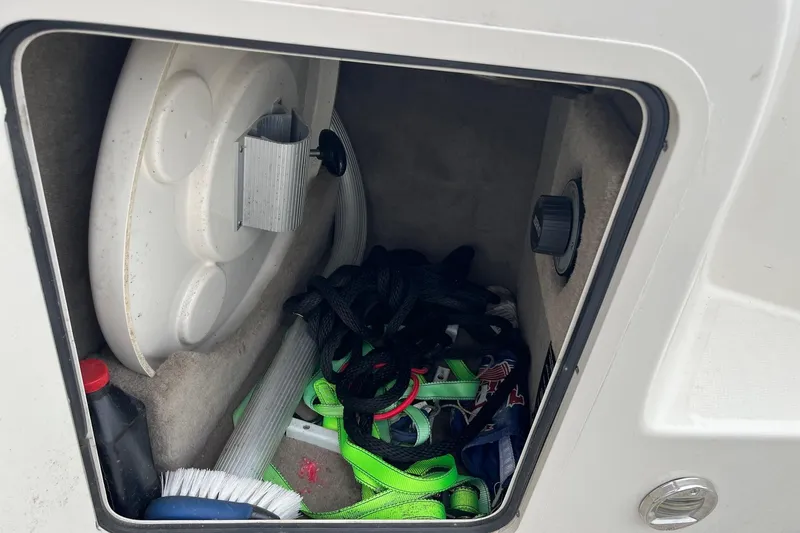 Slide: The Image of Storage compartment of a 2004 Sea Ray 240 Sundancer with boating accessories and equipment. - 11