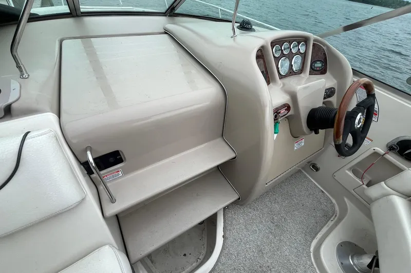 Slide: The Image of 2004 Sea Ray 240 Sundancer helm with steering wheel and instrument panel, overlooking water. - 12