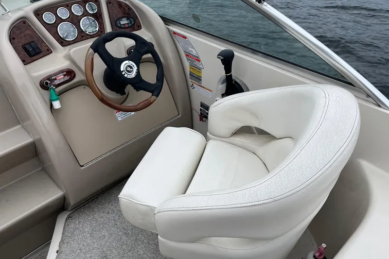 Slide: The Image of 2004 Sea Ray 240 Sundancer helm with steering wheel and white captain's chair. - 14