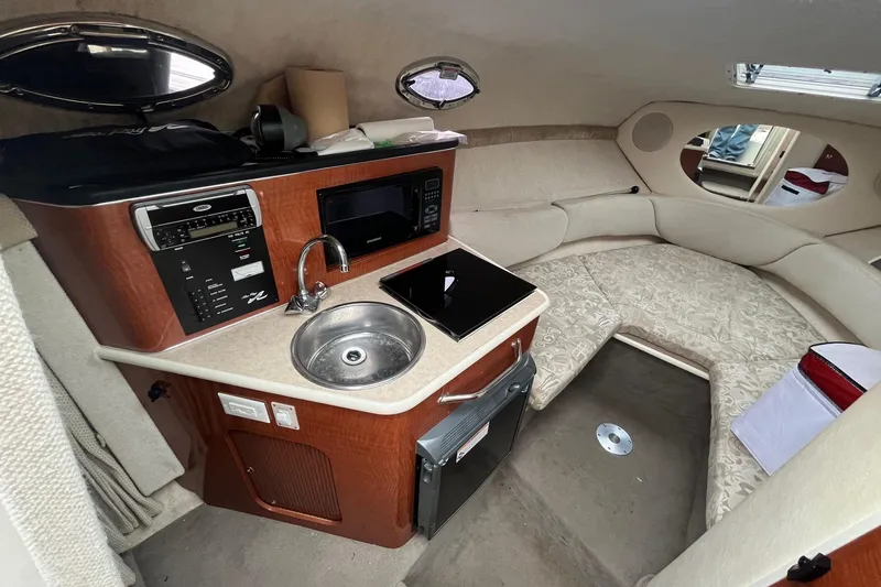 Slide: The Image of 2004 Sea Ray 240 Sundancer cabin interior with kitchenette and seating area. - 20