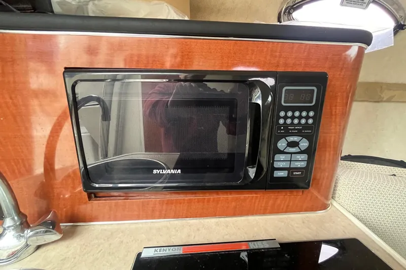 Slide: The Image of Microwave in 2004 Sea Ray 240 Sundancer boat kitchen, featuring wood paneling and modern controls. - 24