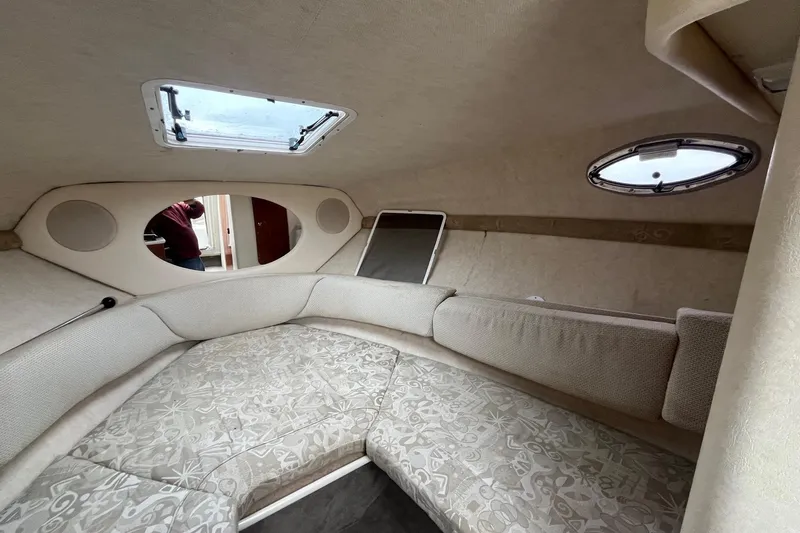 Slide: The Image of Interior cabin of 2004 Sea Ray 240 Sundancer with cushioned seating and porthole windows. - 25