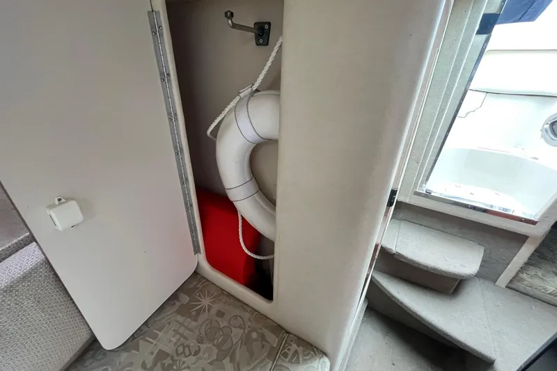 Slide: The Image of 2004 Sea Ray 240 Sundancer interior with life preserver and storage compartment. - 28