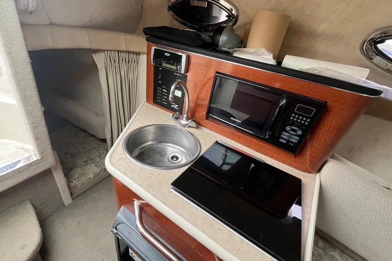 Slide: The Image of 2004 Sea Ray 240 Sundancer cabin kitchenette with sink, microwave, and stove. - 30